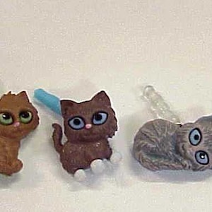 May include: Six small plastic kitten figurines with different colored fur. The kittens are black and white, brown, brown and white, gray and white, and white.