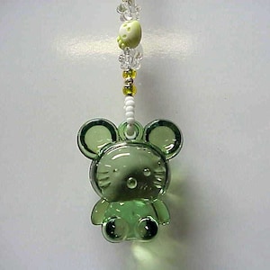 May include: A green glass charm of a cartoon mouse with white bead accents hanging from a white and yellow beaded chain.