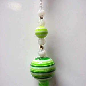 May include: A green and white striped glass bead with a smaller green bead at the bottom, hanging from a white string with white beads.