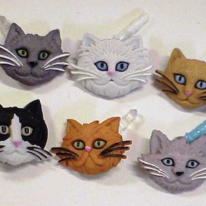 May include: Six colorful cat-shaped buttons with different fur colors and patterns. The buttons have a white background and are made of plastic.