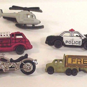 May include: Five miniature toy vehicles: a red fire truck with white ladders, a silver motorcycle, a green and yellow semi-truck with the word "FREIGHT" on the side, a black and white police car with the word "POLICE" on the side, and a white helicopter.