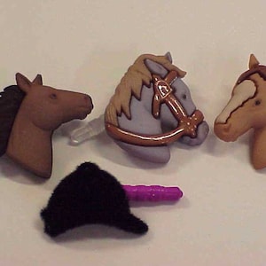 May include: A collection of horse-themed buttons and a black hat. The buttons feature detailed horse head designs in various colors, including brown, tan, and gray, with clear plastic stems. The hat is black and fuzzy, with a purple stem.