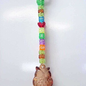 May include: A brown owl charm with a key ring attached to a beaded chain. The beads are multi-colored and spell out the word "MISS" with a red heart bead in the middle.