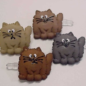 May include: Four plush cat-shaped phone charms in brown, tan, gray, and light brown. Each charm has a white plastic earbud holder attached.