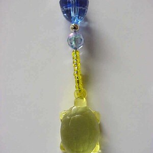 May include: A yellow plastic turtle charm with a blue and clear crystal bead necklace.