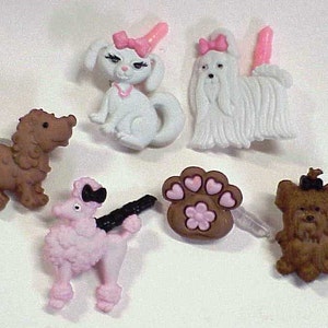 May include: A set of six plastic hair clips featuring different dog breeds. The clips are in various colors, including brown, white, pink, and black. The clips are designed to look like different dog breeds, including a poodle, a Yorkshire Terrier, a Maltese, and a brown dog.