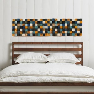 May include: A wooden bed frame with a white headboard and white bedding. The bed is in a bedroom with white walls and a geometric wall art piece above the headboard.