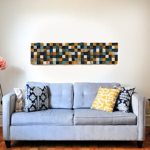 Puede incluir: Un sof&aacute; gris con tres almohadas, una amarilla, una azul y blanca con estampado y una azul con estampado. Una l&aacute;mpara de flores rosa est&aacute; a la izquierda del sof&aacute;. Un arte de pared geom&eacute;trico en blanco y negro est&aacute; sobre el sof&aacute;.