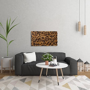 Puede incluir: Un interior de sala de estar con un sof&aacute; gris, una mesa de caf&eacute;, una planta en maceta y una pieza de arte de madera montada en la pared con un patr&oacute;n geom&eacute;trico. La pieza de arte es marr&oacute;n y negra y tiene un dise&ntilde;o moderno.