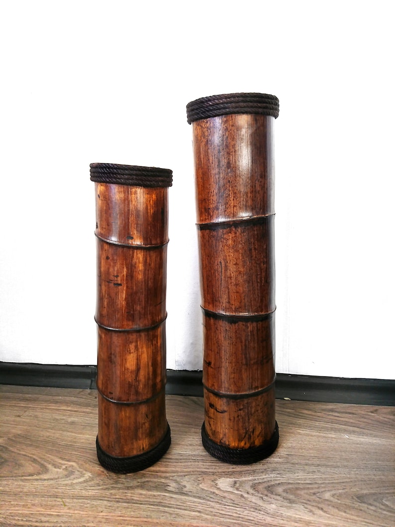 Puede incluir: Dos jarrones de bamb&uacute; marr&oacute;n con ribete de cuerda negra. Los jarrones son de diferentes tama&ntilde;os y est&aacute;n de pie sobre un suelo de madera.