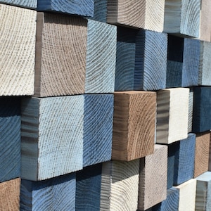 May include: A wall made of various sized wooden blocks, painted in shades of blue, brown, and white. The blocks are arranged in a staggered pattern, creating a textured and visually interesting surface.