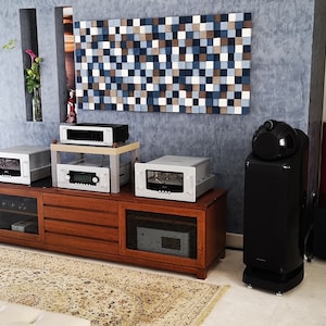May include: A home audio system with two large black speakers, a wooden entertainment center with multiple audio components, and a subwoofer. The speakers have a unique design with a rounded top and a black finish. The entertainment center has a wood grain finish and multiple drawers. The subwoofer is black and has a rounded shape.
