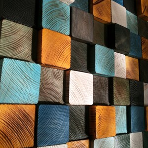 Puede incluir: Una pieza de arte de pared hecha de bloques de madera en varios tonos de azul, marr&oacute;n y blanco. Los bloques est&aacute;n dispuestos en un patr&oacute;n escalonado, creando una textura visualmente interesante.