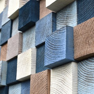 May include: A wall covered in a variety of wooden squares, painted in shades of blue, brown, and white. The squares are arranged in a random pattern, creating a visually interesting and textured surface.