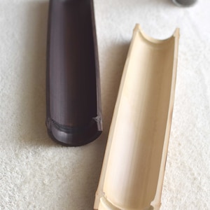 May include: Two bamboo trays, one natural and one stained dark brown. The trays are hollowed out and have a rounded shape.