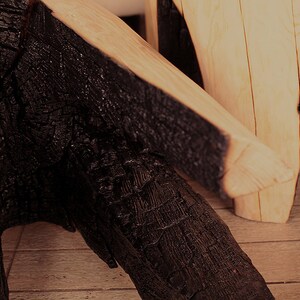 May include: Two wooden stools with black charred edges. The stools are made from natural wood and have a rustic, reclaimed look.