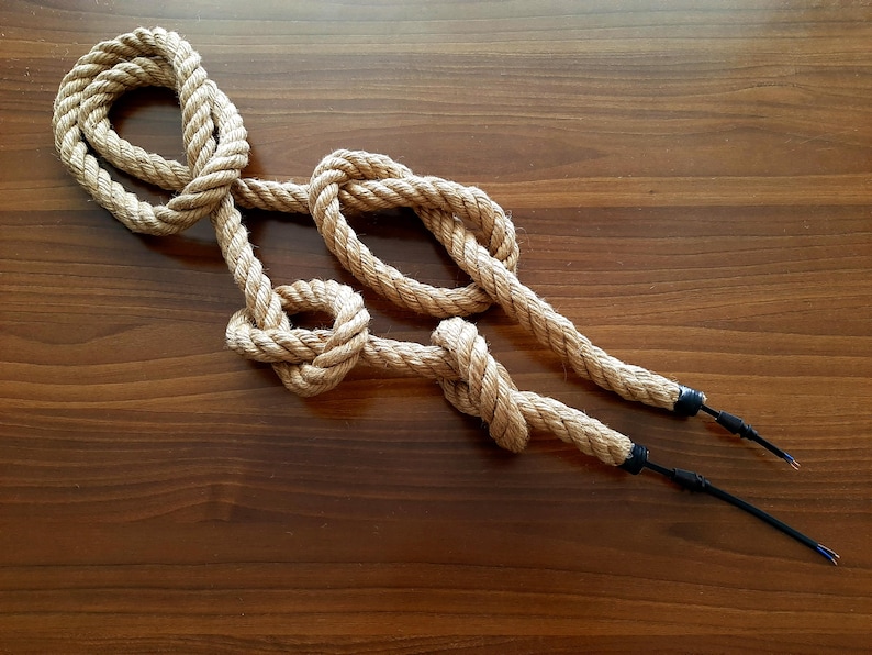 May include: A close-up of a brown rope with two black electrical cords attached to the ends. The rope is tied in a series of knots.