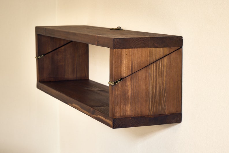 May include: A dark brown wooden shelf with a unique angled design. The shelf is mounted to a wall and has a simple, rustic look.