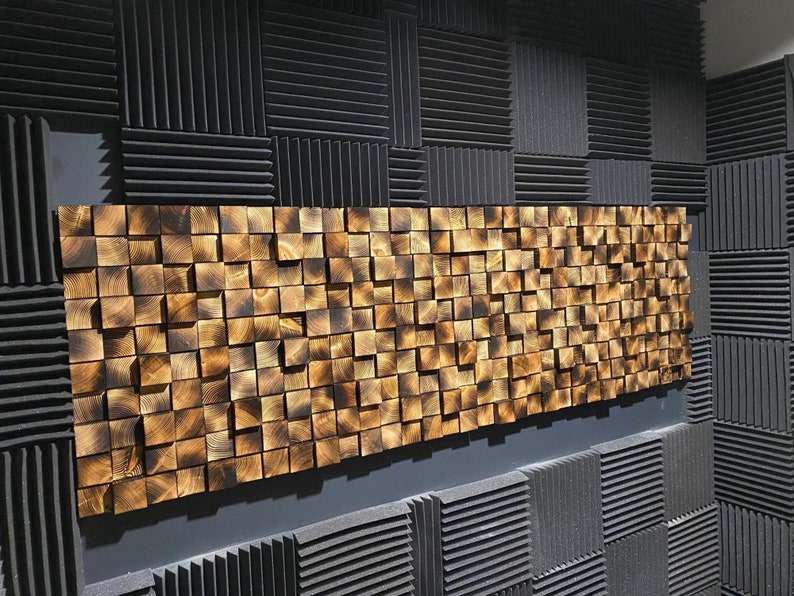 Puede incluir: Una pared cubierta con paneles de espuma ac&uacute;stica negra con un gran panel de madera dorada hecho de cuadrados peque&ntilde;os.