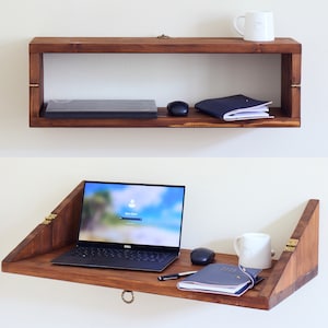 May include: A wooden wall-mounted shelf with a fold-down desk. The shelf has a laptop, a mouse, a notebook, and a mug on it. The desk is folded down and has a laptop, a mouse, a notebook, and a pen on it.