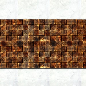 Op de afbeelding: Een wandpaneel gemaakt van kleine, vierkante houten tegels. De tegels zijn in een verspringend patroon gerangschikt en zijn donkerbruin van kleur. Het paneel is rechthoekig en ongeveer 30 cm breed en 90 cm lang.