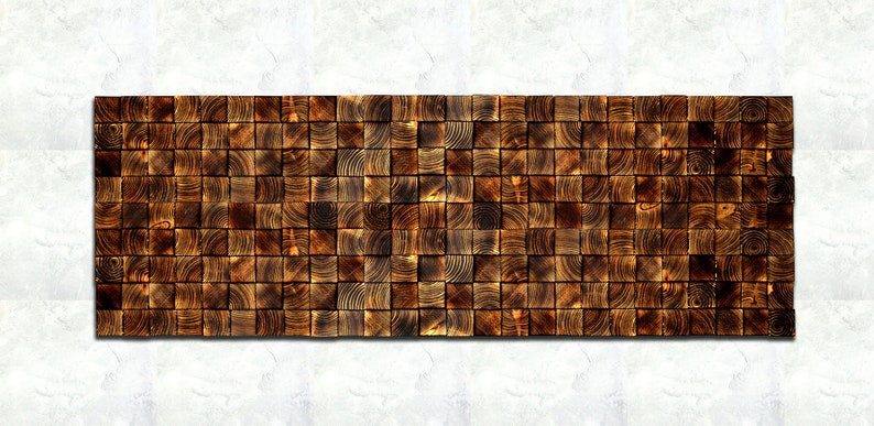Op de afbeelding: Een wandpaneel gemaakt van kleine, vierkante houten tegels. De tegels zijn in een verspringend patroon gerangschikt en zijn donkerbruin van kleur. Het paneel is rechthoekig en ongeveer 30 cm breed en 90 cm lang.