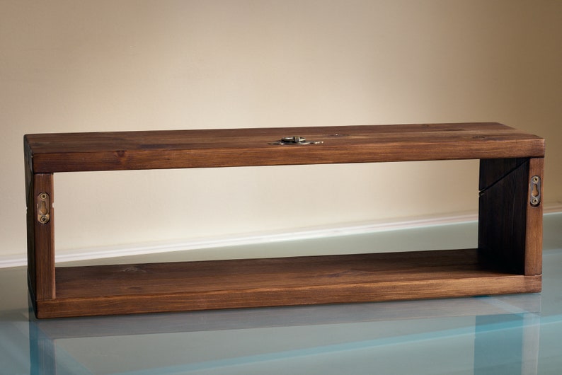 May include: A dark brown wooden shelf with a rectangular open frame. The shelf has a simple design with visible wood grain and is mounted to a wall.