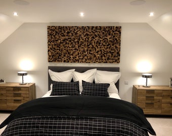 Puede incluir: Una cabecera de cama negra con un edredón a cuadros blanco y negro y almohadas decorativas con estampado blanco y negro. La cama está en un dormitorio con un panel de pared de madera detrás de la cabecera.