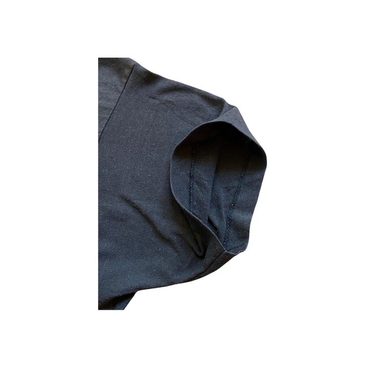 K&ouml;nnte beinhalten: Nahaufnahme eines dunkelgrauen V-Ausschnitt-T-Shirts. Das Bild konzentriert sich auf den &Auml;rmel- und Schulterbereich und zeigt die Stoffstruktur und die Nahtdetails. Das Shirt scheint aus einem weichen, bequemen Material zu sein.