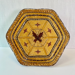 May include: Hexagonal woven basket with a lid. The basket is primarily yellow with dark brown accents and a decorative butterfly in the center. The basket has a textured, woven design.