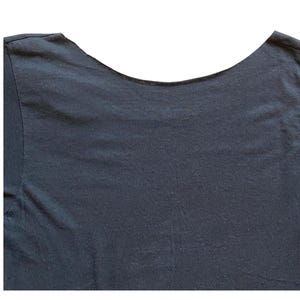 K&ouml;nnte beinhalten: Dunkelblaues T-Shirt mit Rundhalsausschnitt. Der Halsausschnitt ist breit und gebogen, und der Stoff scheint ein weiches, strukturiertes Material zu sein. Die Schultern und der obere R&uuml;cken des T-Shirts sind vor wei&szlig;em Hintergrund sichtbar.