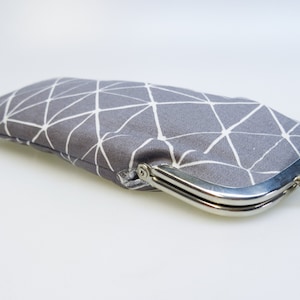 May include: A grey fabric coin purse with a white geometric pattern and a silver clasp.