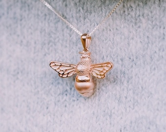 May include: A rose gold necklace with a bee pendant. The bee is detailed with wings and a textured body.
