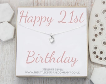 Op de afbeelding: Een zilveren ketting met een klein hartvormig bedeltje in een witte doos met de tekst "Happy 21st Birthday" in roze letters. De doos bevat ook de tekst "Sterling Silver" en "www.thelittlekeepsakecompany.co.uk".