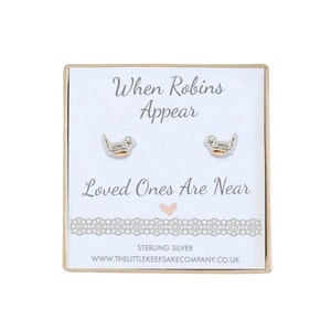 Op de afbeelding: Sterling zilveren oorbellen met een klein roodborstje-ontwerp. De oorbellen worden geleverd in een doos met de tekst "When Robins Appear Loved Ones Are Near" en "Sterling Silver" op de voorkant.