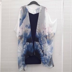 May include: White sheer kimono with a blue and pink floral print. The kimono is open at the front and has a loose fit.