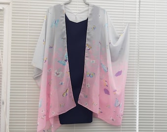 Pode incluir: Um quimono leve e transparente com um design degradê em tons de cinza e rosa. O quimono é decorado com um padrão de borboletas coloridas.