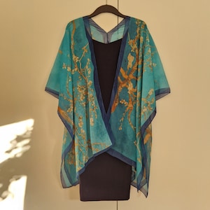 May include: A blue and gold patterned kimono-style wrap with a navy blue sleeveless dress underneath. The wrap has a V-neck and is made of a sheer fabric.