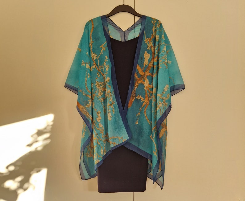 May include: A blue and gold patterned kimono-style wrap with a navy blue sleeveless dress underneath. The wrap has a V-neck and is made of a sheer fabric.