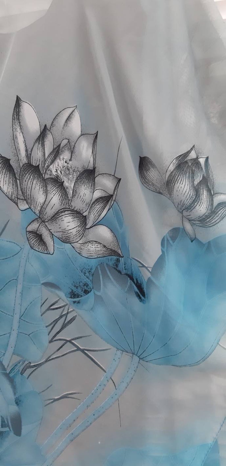 May include: A sheer white curtain with a blue and gray floral pattern. The pattern features lotus flowers and leaves.