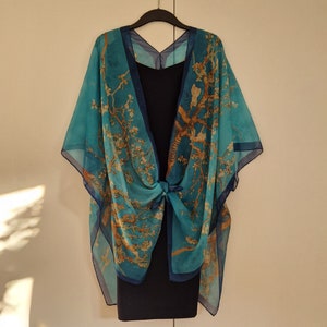 May include: A blue and gold patterned kimono-style wrap with a floral design. The wrap is tied at the waist and has a loose, flowing fit.
