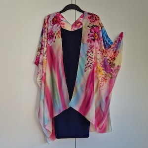 May include: A floral print kimono with a pink, blue, and yellow color scheme. The kimono is draped over a navy blue dress.