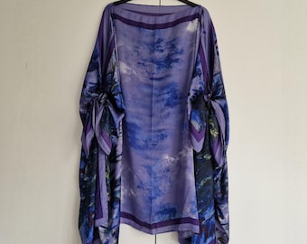 May include: A purple and blue silk scarf with a sky and clouds print. The scarf has a wide border with a darker purple colour.