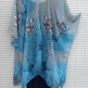 May include: A sheer gray and blue kimono with a floral print of blue and gray lotus flowers. The kimono has a V-neck and is shown hanging on a hanger. The text "Back" is printed below the kimono.