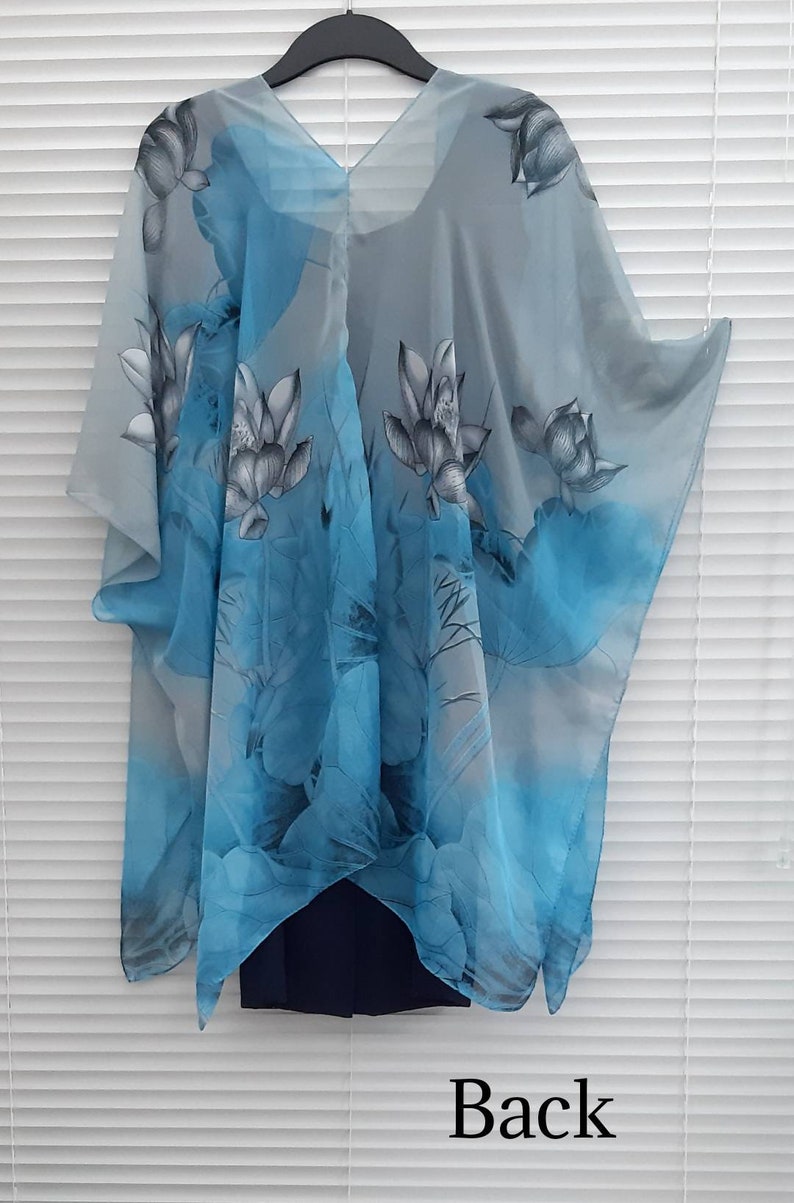 May include: A sheer gray and blue kimono with a floral print of blue and gray lotus flowers. The kimono has a V-neck and is shown hanging on a hanger. The text "Back" is printed below the kimono.