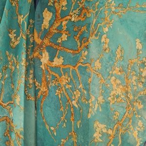 May include: A teal blue silk scarf with a printed design of a stylized tree with yellow blossoms. The scarf is a soft, flowing fabric with a delicate feel.