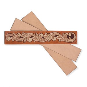 May include: A leather strip with a decorative floral design in brown and tan colors. The strip is accompanied by two additional strips of plain leather.