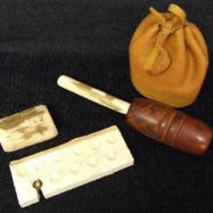 May include: An antique flint and steel fire starting kit. The kit includes a flint, a steel striker, a tinder pouch, and a wooden pipe.