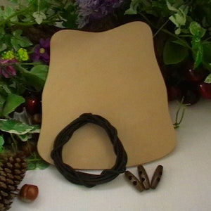 May include: A tan-colored, curved object with a dark brown, circular accent and three wooden toggle buttons. The items are arranged on a white surface with decorative greenery and flowers in the background.