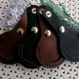 May include: Three leather keyrings in brown, black, and black with a brown trim. Each keyring has a metal snap closure and a loop for attaching keys.